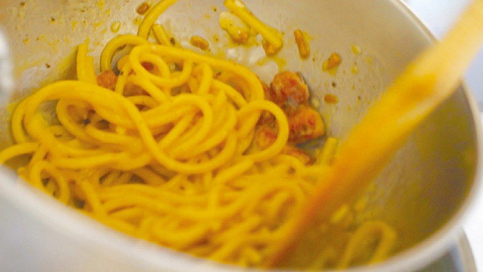 ゆで上げたパスタをベーコンのフライパンで炒め合わせているところ
